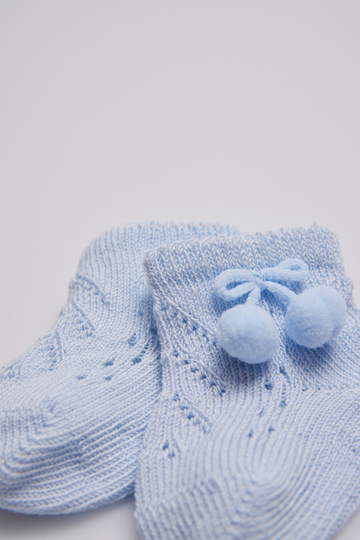Calcetines perlé con borlas recién nacido celeste